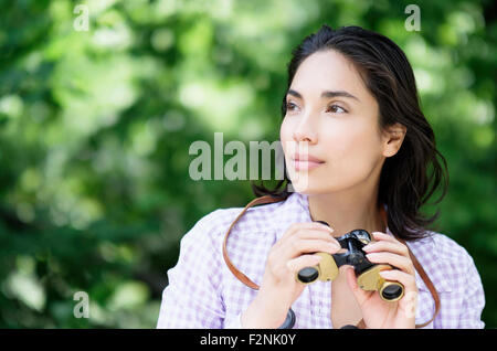 Donna ispanica usando il binocolo all'aperto Foto Stock