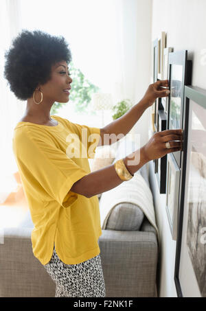 African American donna appendere foto sulla vita della parete della camera Foto Stock