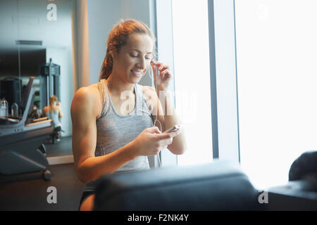 Donna ascoltando mp3 player in palestra Foto Stock