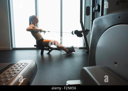 Donna che utilizza macchina ginnica in palestra Foto Stock