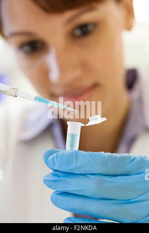 Razza mista scienziato il pipettaggio di campione nella provetta di test in laboratorio Foto Stock