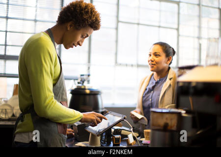 Razza mista barista assistere il cliente nel coffee shop Foto Stock