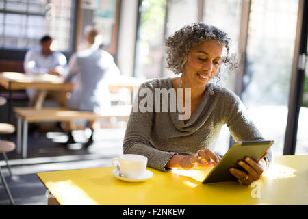 Donna anziana con tavoletta digitale in cafe Foto Stock