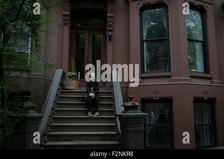 Caucasian donna seduta su townhouse stoop anteriore Foto Stock