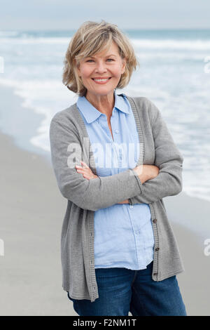 Sorridente donna caucasica permanente sulla spiaggia Foto Stock