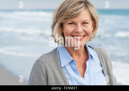 Sorridente donna caucasica camminando sulla spiaggia Foto Stock