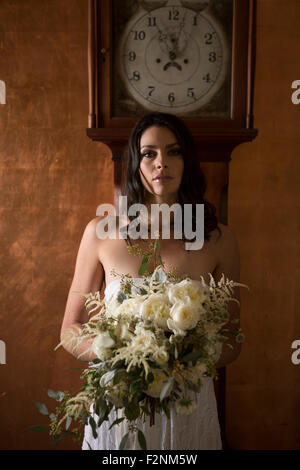 Sposa azienda bouquet di fiori sotto orologio del nonno Foto Stock