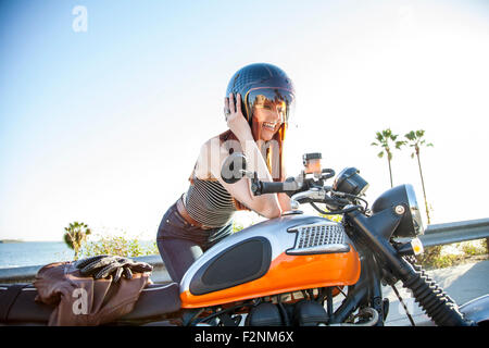 La donna caucasica nel casco seduto sul motociclo Foto Stock