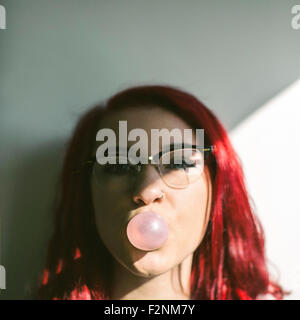 La donna caucasica soffiando bubble gum bubble Foto Stock