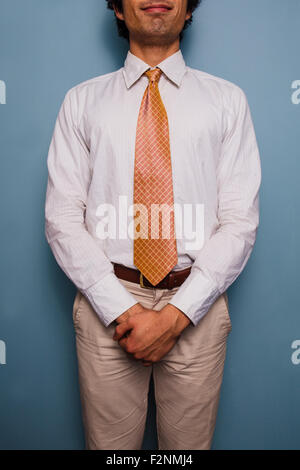 Giovane uomo in piedi da una parete blu, indossa una cravatta Foto Stock