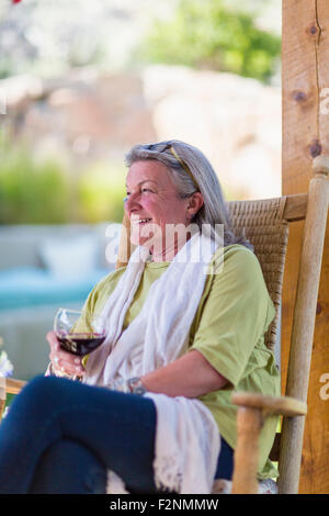 La donna caucasica bere vino sulla veranda Foto Stock