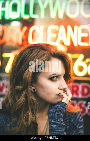 La donna caucasica in piedi nella parte anteriore del segno al neon Foto Stock