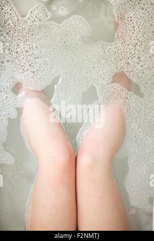 Angolo di alta vista delle gambe della donna in ammollo nella vasca da bagno Foto Stock