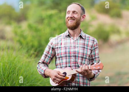 Uomo caucasico giocando ukulele all'aperto Foto Stock