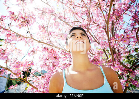 Ispanico donna in piedi sotto la fioritura tree Foto Stock