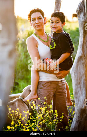 Madre ispanica che porta il figlio in giardino Foto Stock