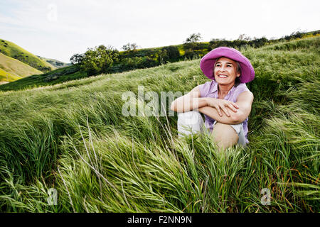 Caucasian donna seduta in erba alta Foto Stock