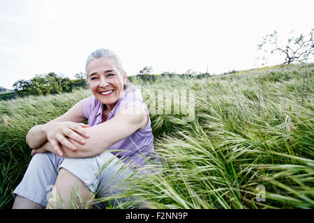 Caucasian donna seduta in erba alta Foto Stock