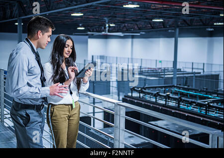 La gente di affari con tavoletta digitale oltre la sala server Foto Stock