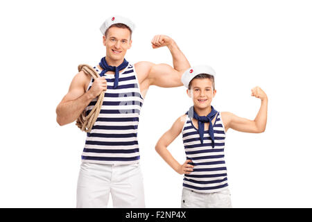 Giovane uomo e un bambino in sailor uniformi che mostra bicipite e guardando la telecamera isolata su sfondo bianco Foto Stock