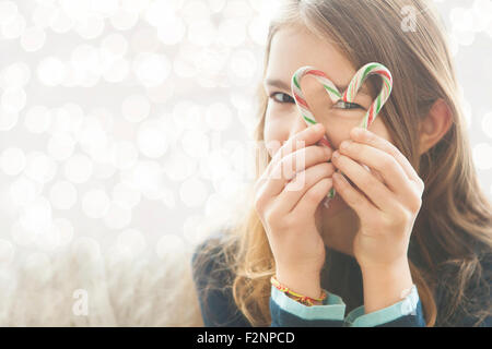 Ragazza caucasica guardando attraverso il cuore-forma con candy canes Foto Stock