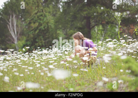 Ragazza caucasica accovacciato in campo di fiori Foto Stock