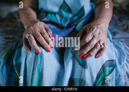 Close up di mani di donna più anziana in appoggio sulle ginocchia Foto Stock