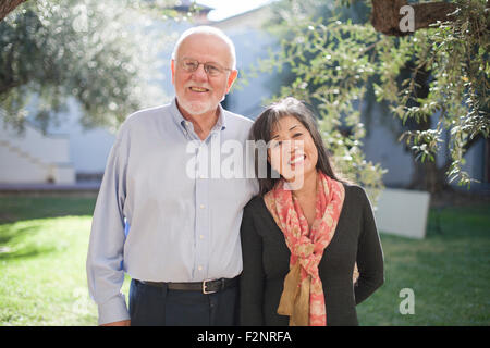 Anziana coppia sorridente in cortile Foto Stock