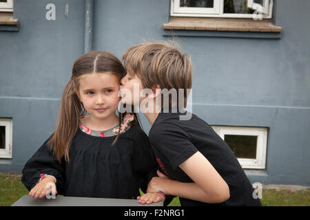 Ragazzo caucasico kissing sorella in cortile