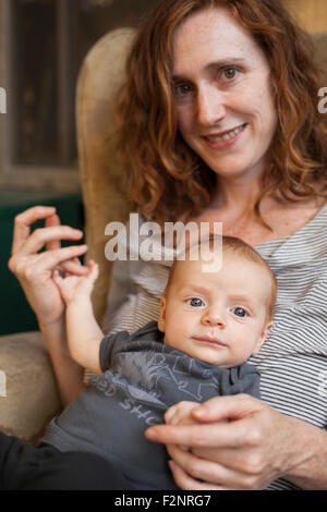 Sorridente azienda madre bambino in poltrona Foto Stock