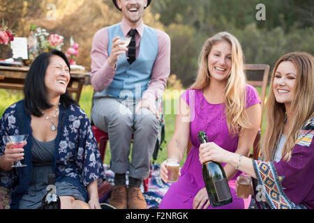 Gli amici a bere champagne a picnic nel parco Foto Stock