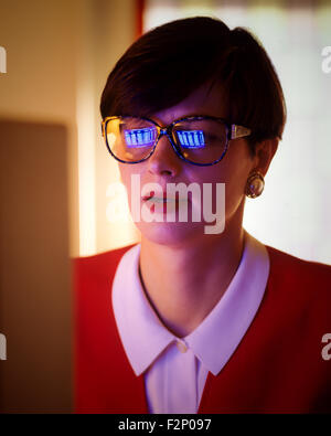 Imprenditrice donna con schermo di computer si riflette nei suoi occhiali, illuminato dalla luce del computer Foto Stock