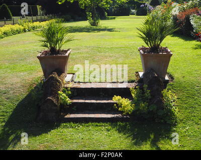 Vasi di fiori a Chenies Manor Garden, dal lato della Manorhouse, che mostrano le fasi fino a Prato nel tardo pomeriggio di sole. Foto Stock