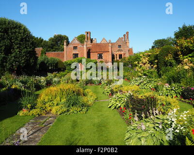 Chenies Manor House e affondata giardino con splendidi fiori perenni frontiere e freschi Fogliame verde;soleggiato con cielo blu. Foto Stock