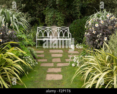 Il giardino bianco,Chenies Manor in tarda estate mostra white dalie,verde variegato foglie,pietre per pavimentazione e bianco sedile unico. Foto Stock