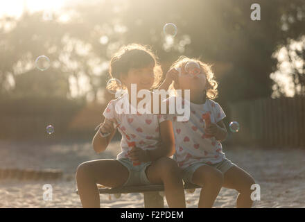 Due piccole sorelle rendendo le bolle di sapone nel parco al crepuscolo Foto Stock