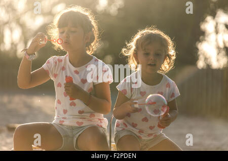 Due piccole sorelle rendendo le bolle di sapone nel parco al crepuscolo Foto Stock