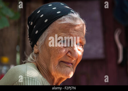 Outdoor ritratto di una vecchia donna nel fazzoletto con razzi di sun sul suo viso. Primo piano. Foto Stock