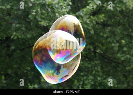 Gigantesche bolle di sapone creato con funi e bastoni in un parco Foto Stock