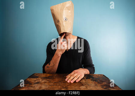 Confuso giovane con sacchetto di carta sopra la sua testa Foto Stock