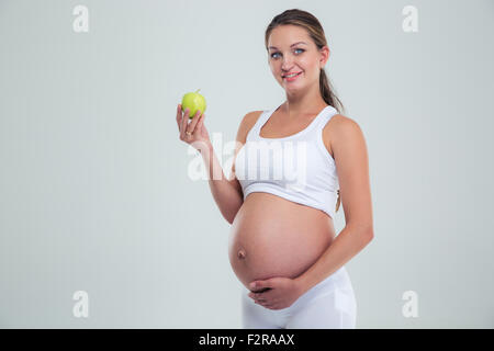 Ritratto di un felice donna incinta azienda apple isolato su uno sfondo bianco e guardando la fotocamera Foto Stock