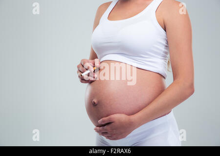 Closeup ritratto di una donna incinta Sigaretta fumare isolato su uno sfondo bianco Foto Stock