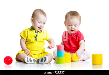 Carino i bambini a giocare con i colori dei giocattoli. Bambini ragazza e ragazzo seduto sul pavimento. Isolato su sfondo bianco. Foto Stock