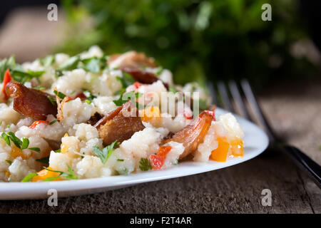 La piastra con il tradizionale cibo piccante chiamato pilaf, su sfondo di legno. Cucinato con il fritto di pollo, riso, aglio e carota Foto Stock