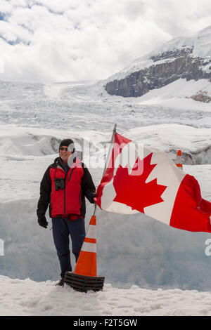 Tourist in posa con la bandiera canadese sul Ghiacciaio Athabasca, nelle montagne rocciose, Alberta, Canada, America del Nord. Foto Stock