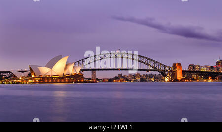 Sydney Australia punti di riferimento della città al tramonto illuminati e riflettendo in sfocato acque del porto di Sydney Foto Stock