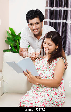 2 indian coppia sposata incinta home salotto con divano libro di lettura Foto Stock