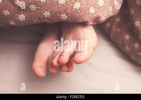 Giovane donna di piedi nel letto sotto i coperchi Foto Stock