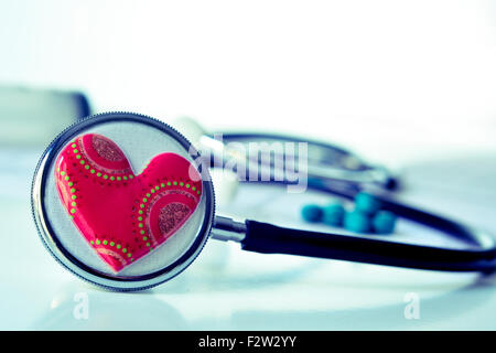 Primo piano di un cuore rosso su uno stetoscopio per la salute cardiovascolare Foto Stock