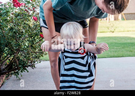 A un anno di età del bambino caucasico ragazza cammina con l'aiuto di sua zia. Stati Uniti d'America Foto Stock